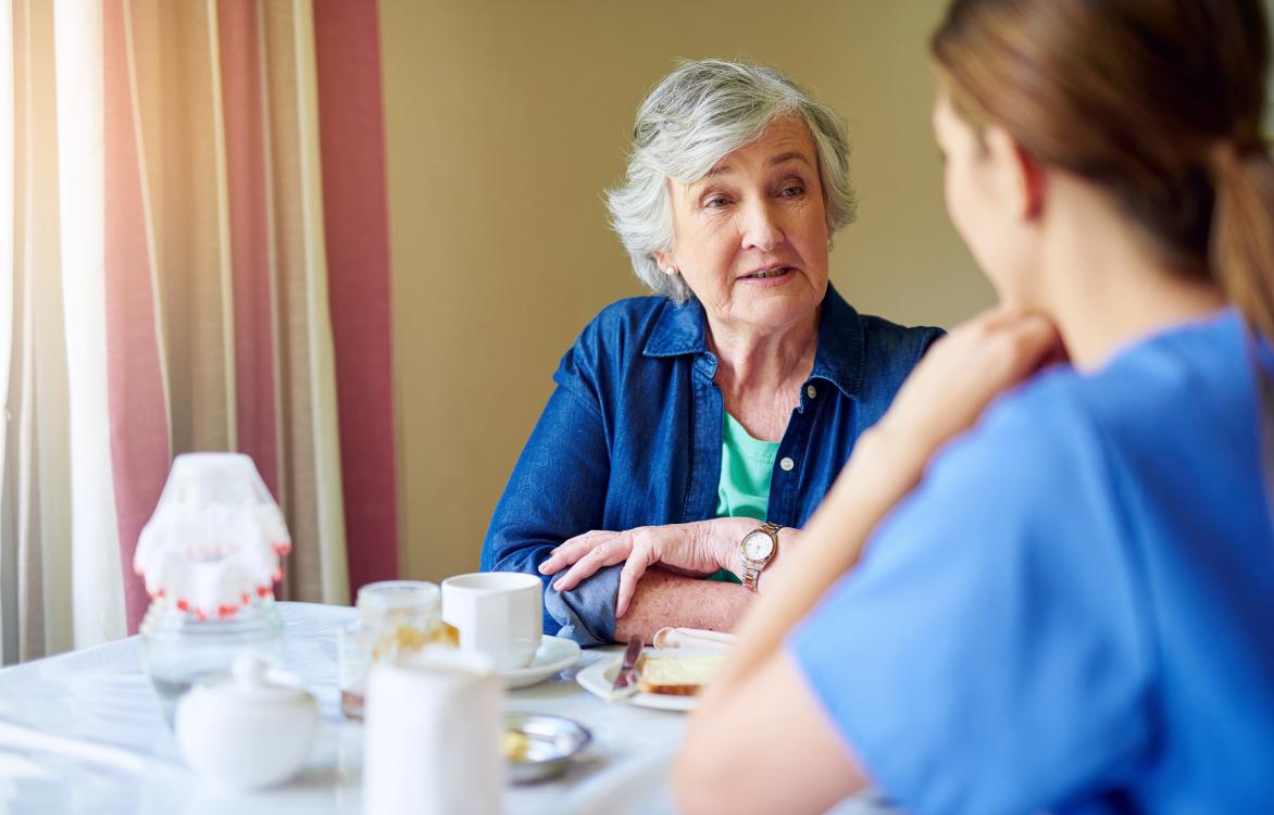 oudere vrouw en verpleegster aan tafel